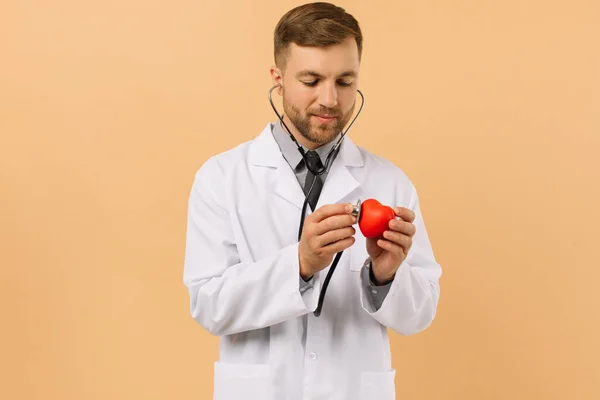 Cardiologista Médico Masculino Escuta Coração Com Estetoscópio Fundo Bege — Fotografia de Stock