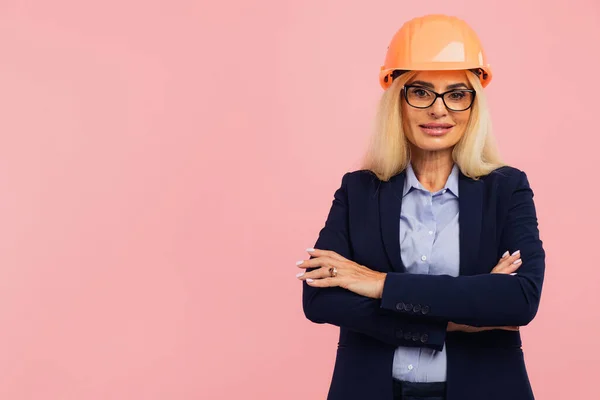 stock image Portrait of a mature woman architect or engineer in glasses on a pink background