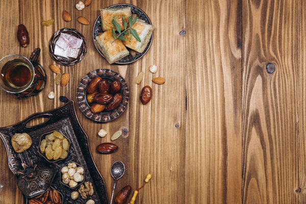 Сухие финики и чай на деревянном столе. Арабские традиционные блюда, кастрюли и фрукты. Рамадан Карим, концепция праздника Ид мубарак. Вид сверху. Плоский лежал. Копирование пространства