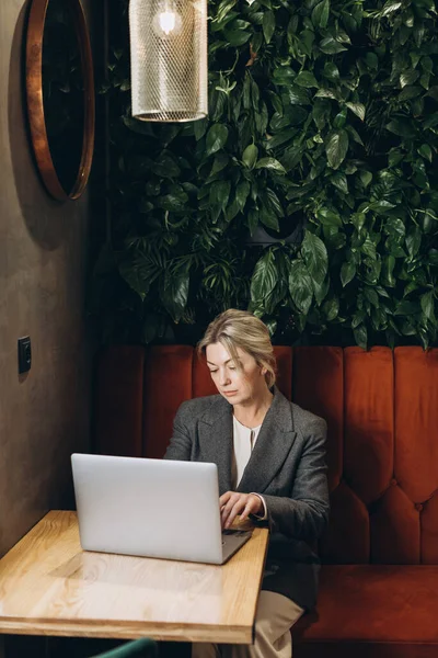 Mature business woman restaurant administrator sitting and working on laptop