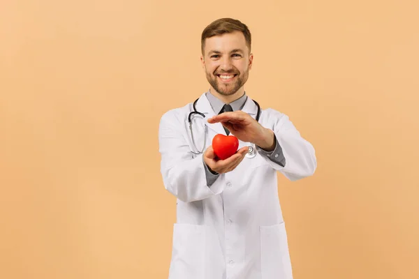 Médico Cardiólogo Masculino Sostiene Corazón Sobre Fondo Beige — Foto de Stock