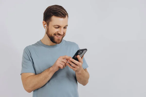 Lachende Man Met Oordopjes Vasthouden Kijken Naar Zijn Smartphone — Stockfoto