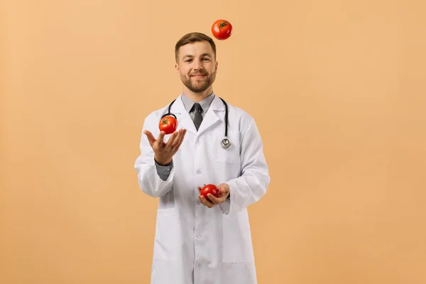 Mužský Nutriční Lékař Stetoskopem Úsměvem Žonglování Rajčat Béžovém Pozadí Dietní — Stock fotografie