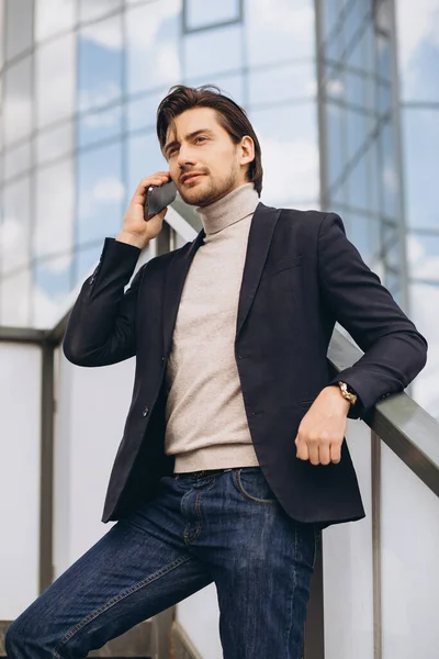 穿着西装的英俊快乐男性商人在城市建筑和办公室的背景下通过电话交谈的画像 — 图库照片