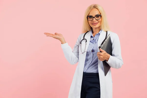 Dojrzała Kobieta Lekarz Okularach Folderu Gospodarstwa Stetoskop Pokazać Coś Przestrzeni — Zdjęcie stockowe