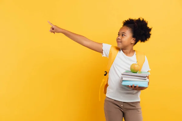 アフリカ系アメリカ人の女子学生がノートや本を持ち 黄色の背景に何かを表示し スペースをコピー — ストック写真