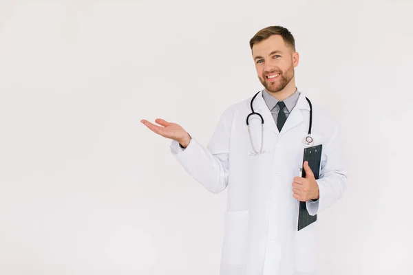 フォルダを持つ幸せな男性医師は 白い背景にコピースペースに何かを示しています — ストック写真
