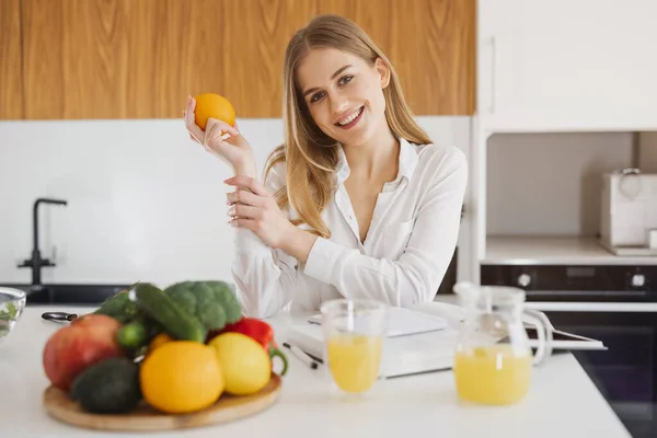 Söt Blond Kvinna Håller Orange Och Tittar Receptbok Köket — Stockfoto