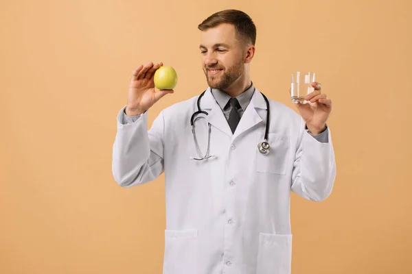 Médico Nutricionista Masculino Con Estetoscopio Sonriendo Sosteniendo Agua Manzana Sobre —  Fotos de Stock