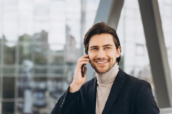 在城市建筑和办公室的背景下 穿着西装的英俊的现代男性商人的画像 通过电话交谈 微笑着 — 图库照片