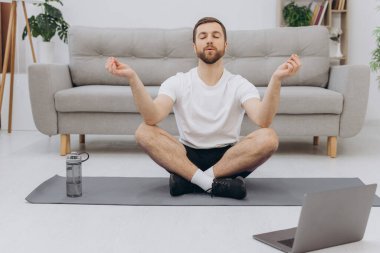 Karantinada sakin olun. Millennial elemanı antrenörle internetten laptopla meditasyon yapıyor. Boş alan.