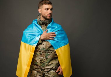 Ukrayna bayrağıyla bağlı cesur bir Ukraynalı askerin portresi ve el ele tutuşan bir kalp, özgürlük konsepti