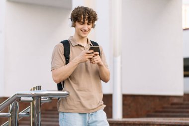Çekici kıvırcık erkek üniversitesi ya da kampüste telefonla dolaşan üniversite öğrencisi.