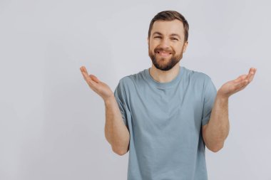 Mavi tişörtlü, modern sakallı orta yaşlı bir adamın portresi, beyaz arka plandaki duyguları bilmediğini gösteriyor.