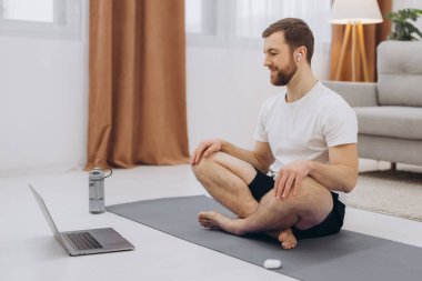 Karantinada sakin olun. Millennial elemanı antrenörle internetten laptopla meditasyon yapıyor. Boş alan.