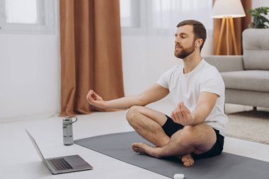 Karantinada sakin olun. Millennial elemanı antrenörle internetten laptopla meditasyon yapıyor. Boş alan.