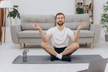 Karantinada sakin olun. Millennial elemanı antrenörle internetten laptopla meditasyon yapıyor. Boş alan.