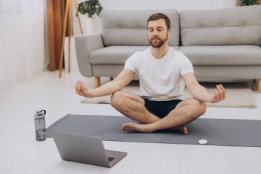 Karantinada sakin olun. Millennial elemanı antrenörle internetten laptopla meditasyon yapıyor. Boş alan.