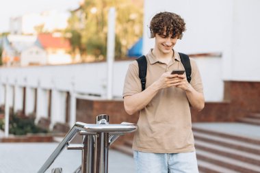 Çekici kıvırcık erkek üniversitesi ya da kampüste telefonla dolaşan üniversite öğrencisi.