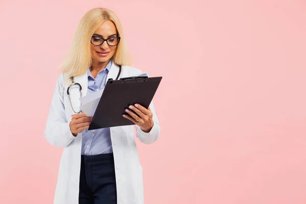 Dojrzałe Kobieta Lekarz Okulary Stetoskop Gospodarstwa Folderu Różowym Tle Miejsca — Zdjęcie stockowe