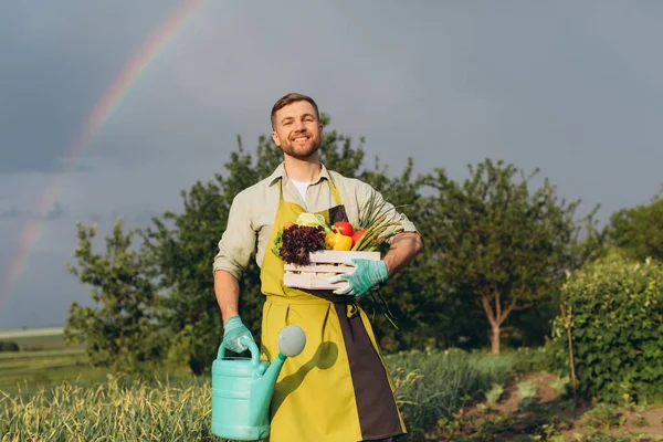快乐的园丁 拿着菜篮 背景是彩虹和花园 园艺的概念 — 图库照片