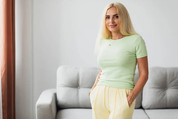 stock image Attractive blonde middle-aged woman in living room at home