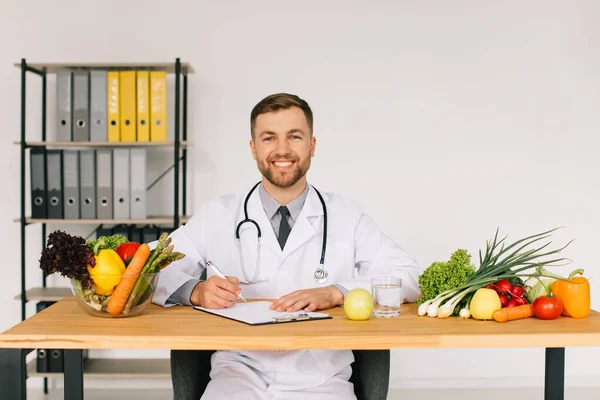 Szczęśliwy Lekarz Dietetyk Siedzi Miejscu Pracy Biurze Wśród Świeżych Warzyw — Zdjęcie stockowe