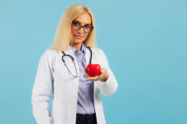 Dojrzała Kobieta Lekarz Okularach Stetoskopem Trzymającym Serce Niebieskim Tle Przestrzenią — Zdjęcie stockowe