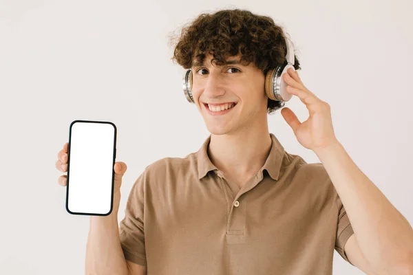 Portret Atrakcyjnego Młodzieńca Słuchawkach Smartfonem Białym Ekranem Przestrzenią Kopiowania Lista — Zdjęcie stockowe