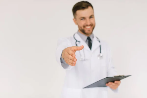 聴診器とフォルダを持つ幸せな医者は白い背景に挨拶の手を伸ばし — ストック写真