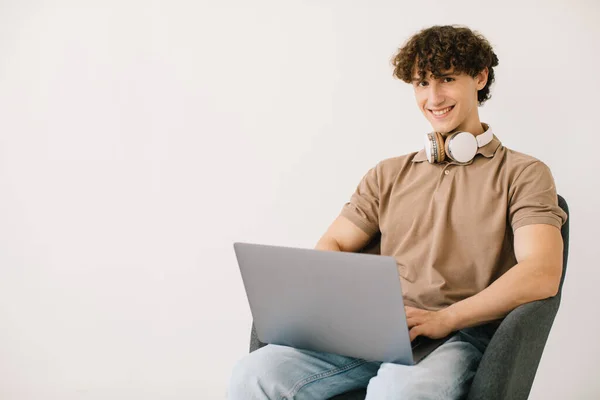 Jovem Atraente Usando Laptop Usando Fones Ouvido Enquanto Sentado Poltrona — Fotografia de Stock