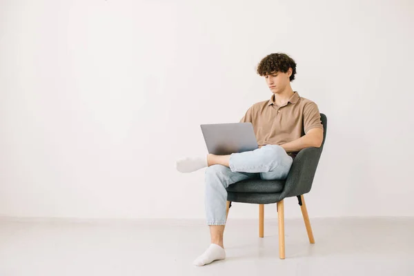 Pemuda Yang Menarik Menggunakan Laptop Sambil Duduk Kursi Menghadap Dinding — Stok Foto
