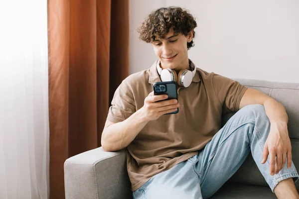 Retrato Joven Hombre Pelo Rizado Feliz Usando Teléfono Inteligente Mientras — Foto de Stock