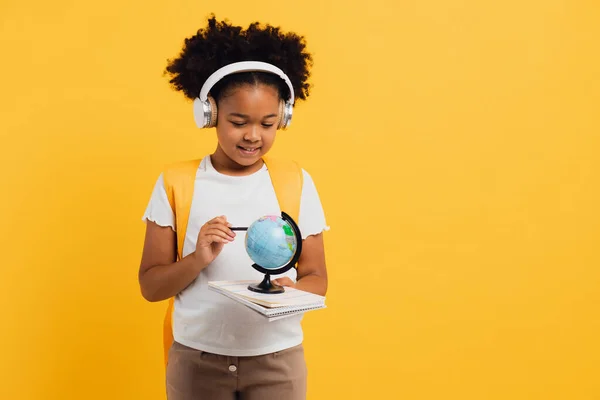 幸せなアフリカ系アメリカ人の女子高生のヘッドフォンでバックパックを見地理的な世界 コピースペース — ストック写真