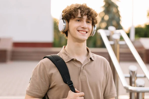 Çekici Kıvırcık Saçlı Kulaklıklı Gülümseyen Erkek Öğrencinin Portresi — Stok fotoğraf