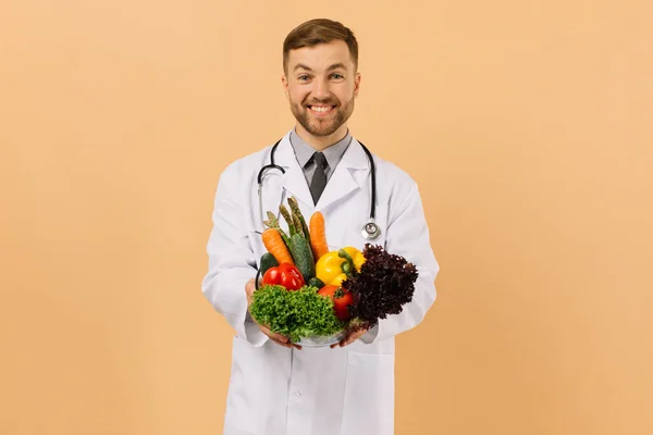 Ευτυχισμένη Διατροφολόγος Αρσενικό Γιατρό Στηθοσκόπιο Δείχνει Φρέσκα Λαχανικά Μπεζ Φόντο — Φωτογραφία Αρχείου