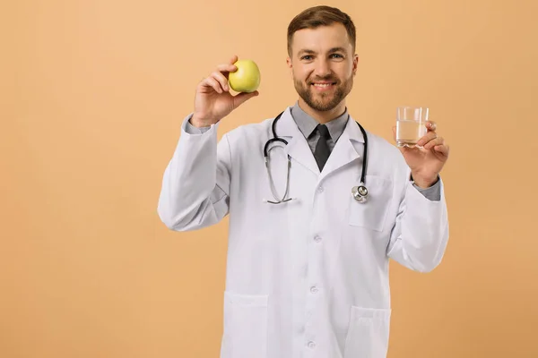 Steteskoplu Erkek Beslenme Uzmanı Gülümsüyor Bej Arka Planda Elma Tutuyor — Stok fotoğraf