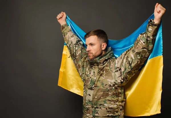 stock image Portrait of a courageous Ukrainian military man holding the flag of Ukraine, freedom concept