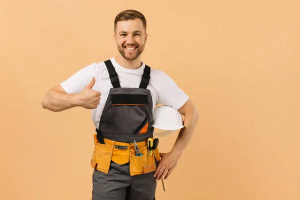 Positive Männliche Reparaturarbeiter Hause Hält Einen Helm Und Zeigt Perfekt — Stockfoto