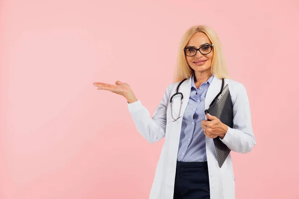 Dojrzała Kobieta Lekarz Okularach Folderu Gospodarstwa Stetoskop Pokazać Coś Przestrzeni — Zdjęcie stockowe