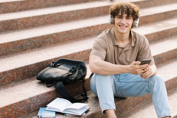 Atractivo Rizado Joven Estudiante Universitario Universitario Sienta Las Escaleras Mirando —  Fotos de Stock
