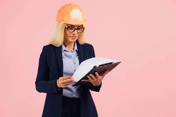 有魅力的成熟女建筑师或戴眼镜的女工程师的肖像用带有粉色背景文件的文件夹 — 图库照片