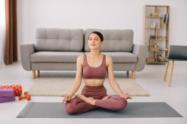 Çekici ve sağlıklı genç bir kadın evde dinlenirken yoga egzersizleri yapıyor.