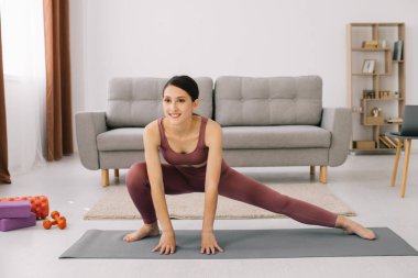 Çekici ve sağlıklı genç kadının evde istirahat ederken egzersizleri yapması