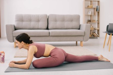 Çekici ve sağlıklı genç kadının evde istirahat ederken egzersizleri yapması