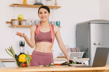 Mutlu spor kadının portresi taze elma tutuyor ve bisepsleri mutfakta gösteriyor, sağlıklı beslenme konsepti.