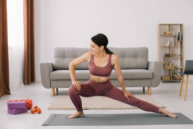 Çekici ve sağlıklı genç kadının evde istirahat ederken egzersizleri yapması