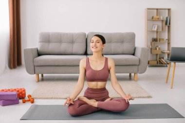 Çekici ve sağlıklı genç bir kadın evde dinlenirken yoga egzersizleri yapıyor.