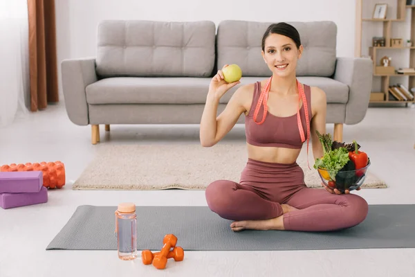 Joven Mujer Deportiva Sentada Esterilla Yoga Sosteniendo Variedad Verduras Manzana — Foto de Stock