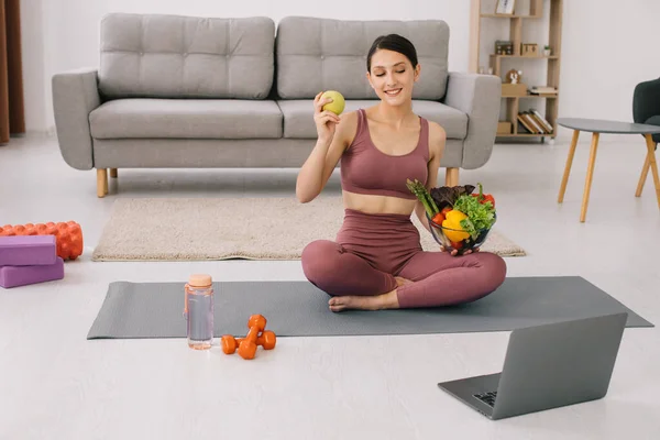 Stock image Athletic young woman blogger nutritionist holds vegetables and leads a video call on proper nutrition